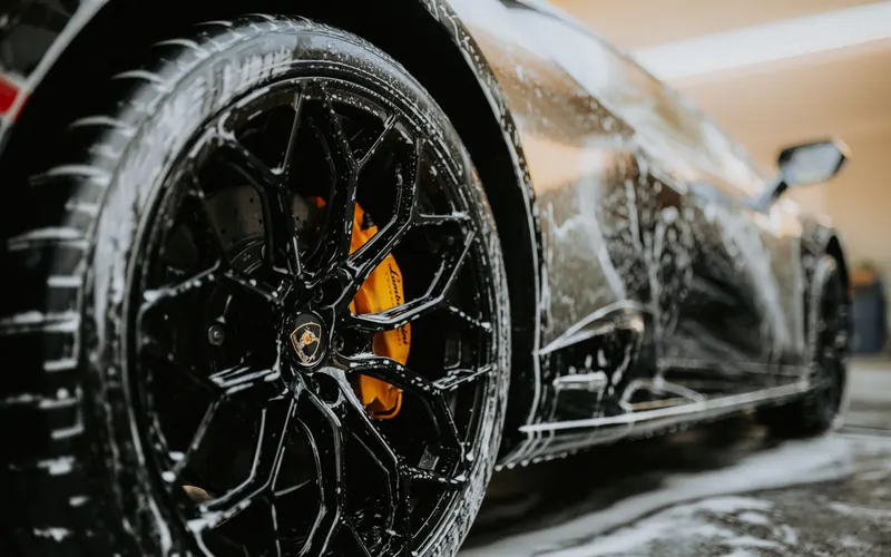 An alloy wheel and brake caliper covered in cleaning foam